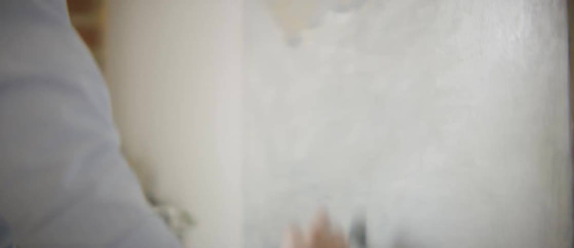 A young woman applies broad brush strokes to an art canvas