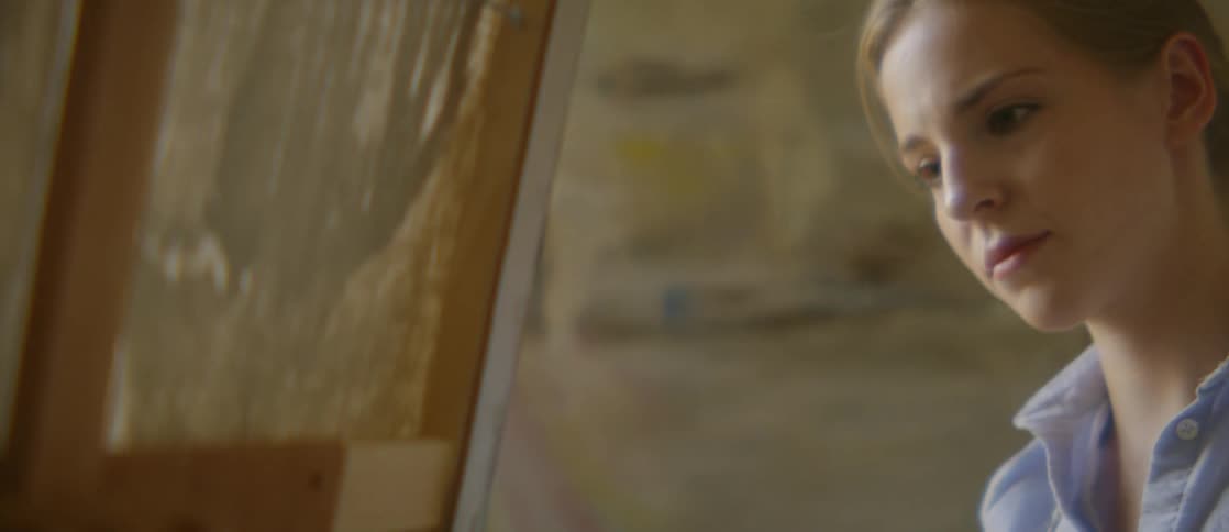 Young woman paints on canvas with large brush