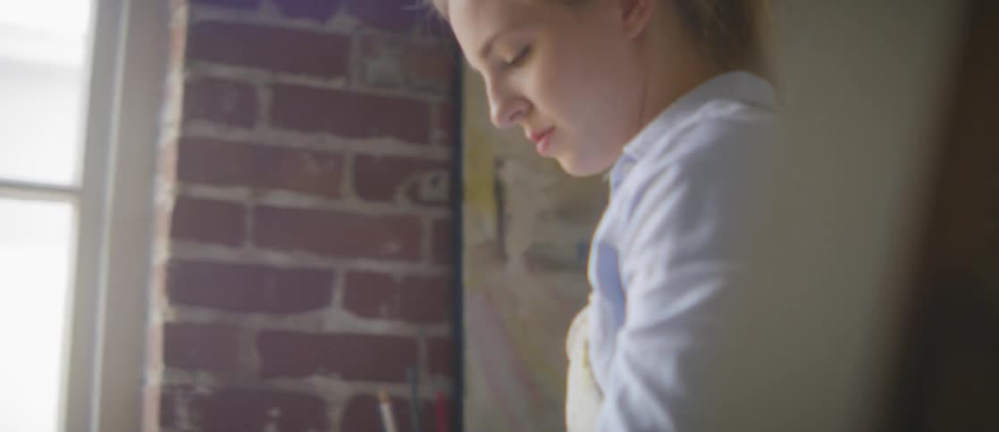 Female artist working on a palette in a well lit brick studio