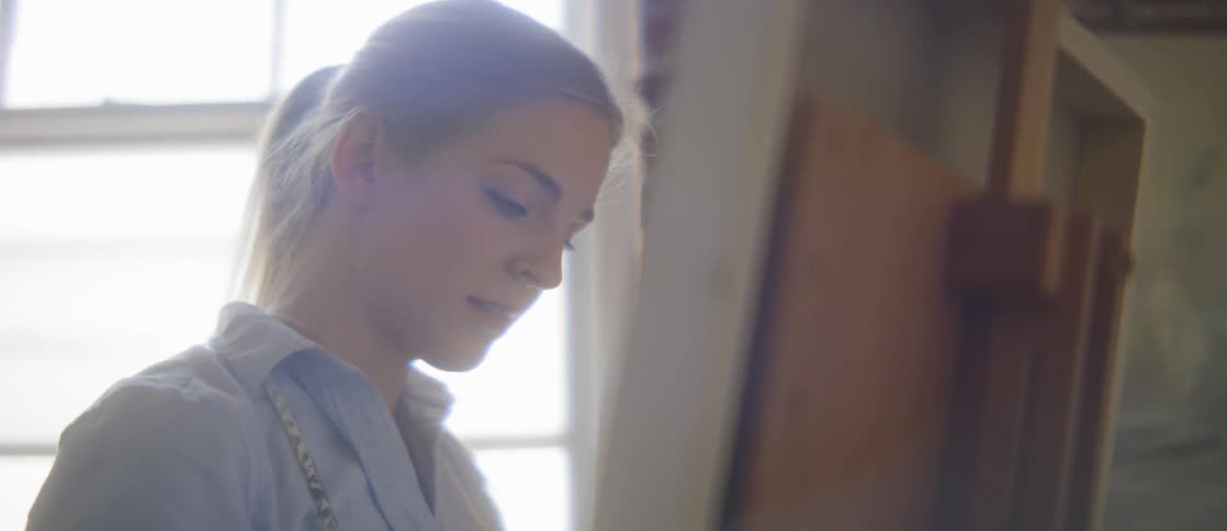 A woman is painting by the window