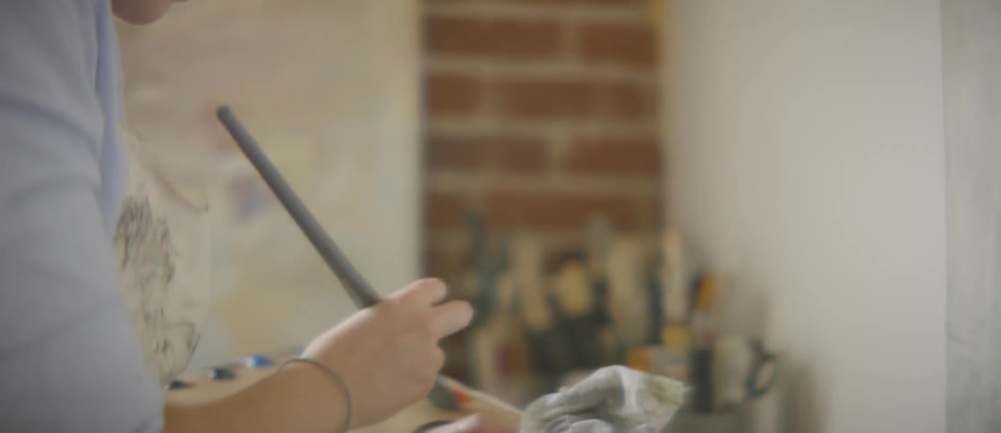 A woman is mixing paint colors together