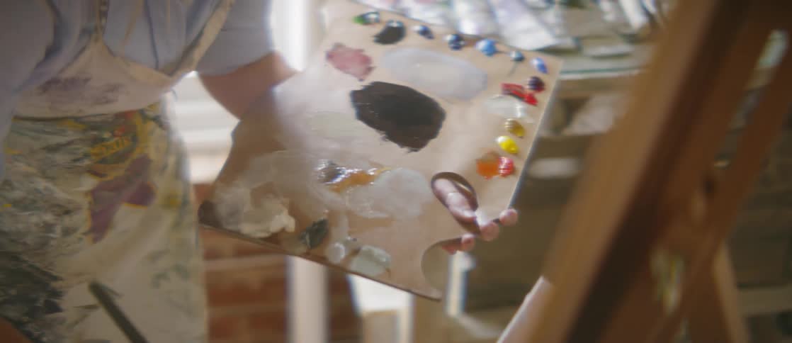 Person paints a picture holding a board filled with paints