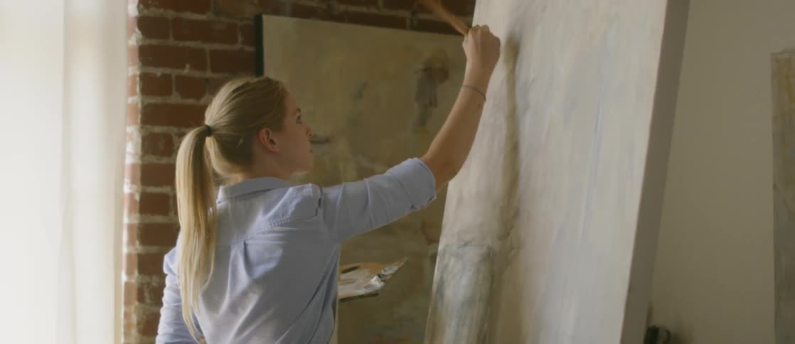 A woman painting a canvas in a studio