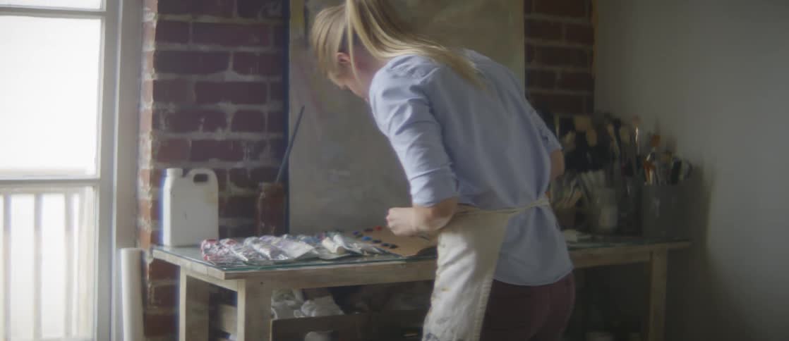 An artist adds paint to a palette in an art studio