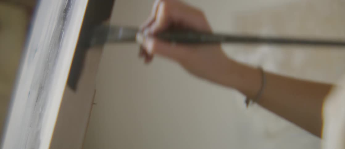 An artist painting black on the corners of a canvas