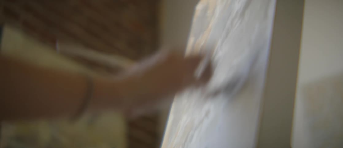 Woman paints a picture on easel indoors during the daytime