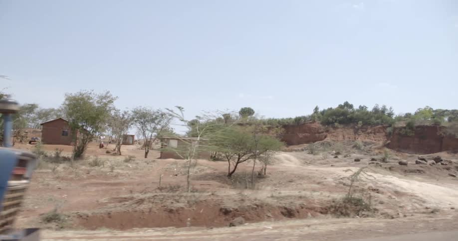 A wood laden tractor on a dirt road in a hot landscape