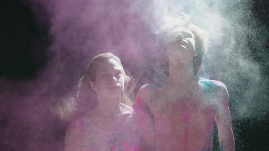 A young man and a young woman with chalk dust in their hair throw their heads backwards