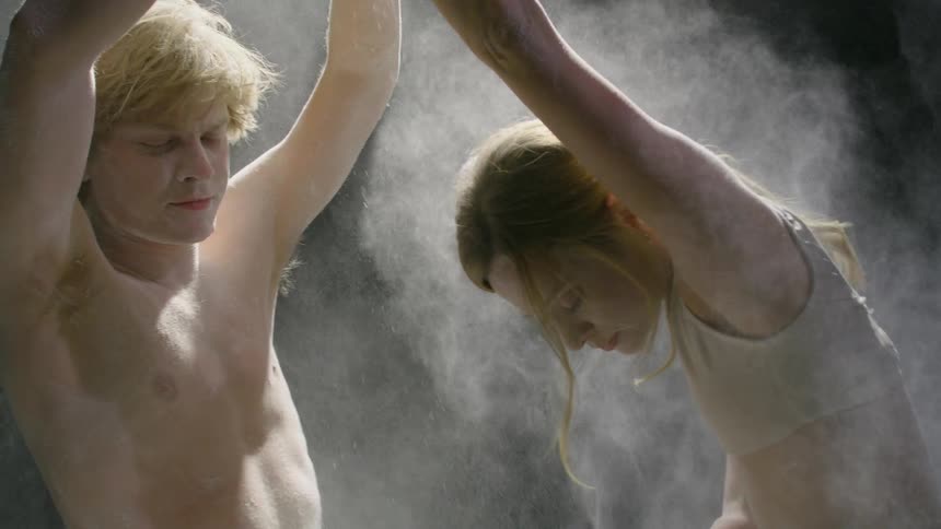 A man and woman get hit with white dirt as they dance