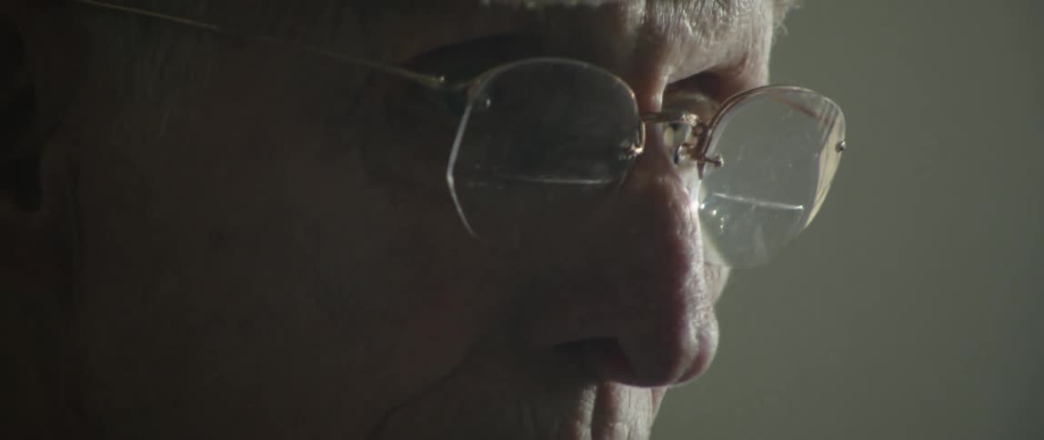 Man in hat and glasses focuses on something he's working on with his hands