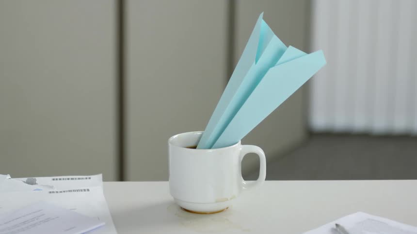 A paper airplane goes into a cup