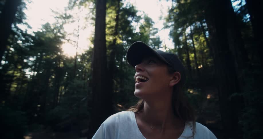 Woman in hat looks up in forest