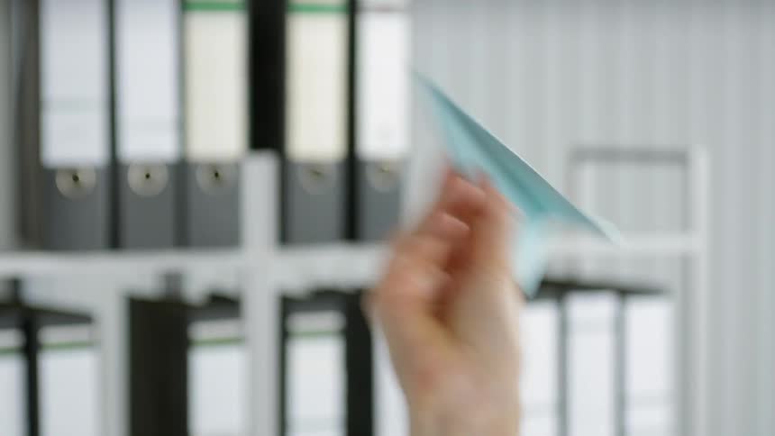 A hand is raised and throws a paper airplane