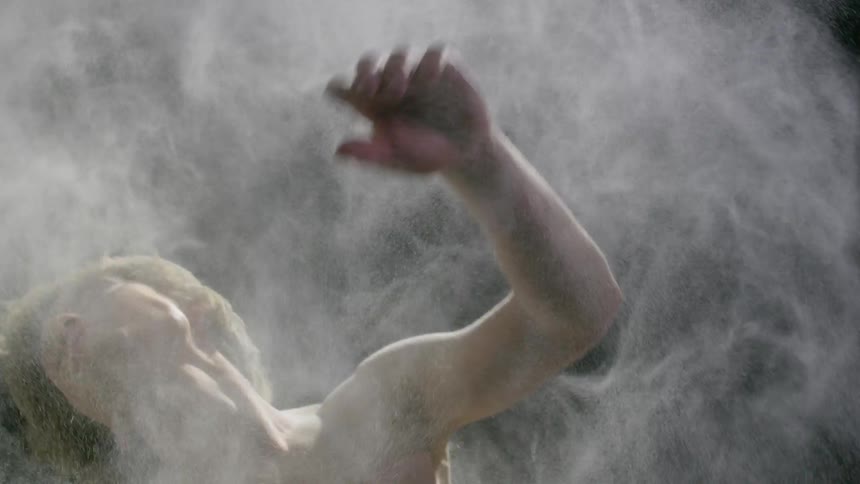 A man is dancing with dust all around
