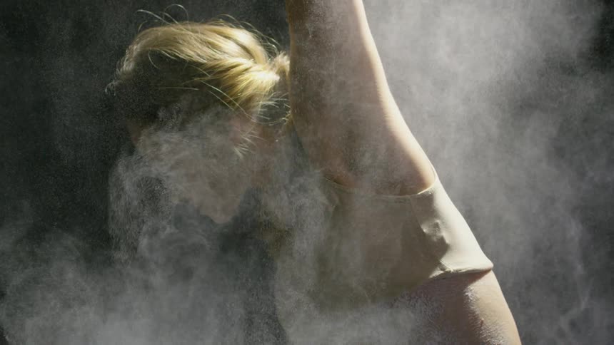 A dancer in a pose while white powder is thrown on her