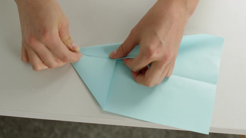 Person folds a blue sheet of paper