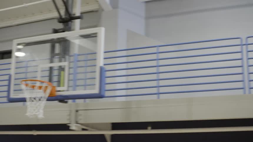 A man on a basketball court shoots a basketball and makes the basket