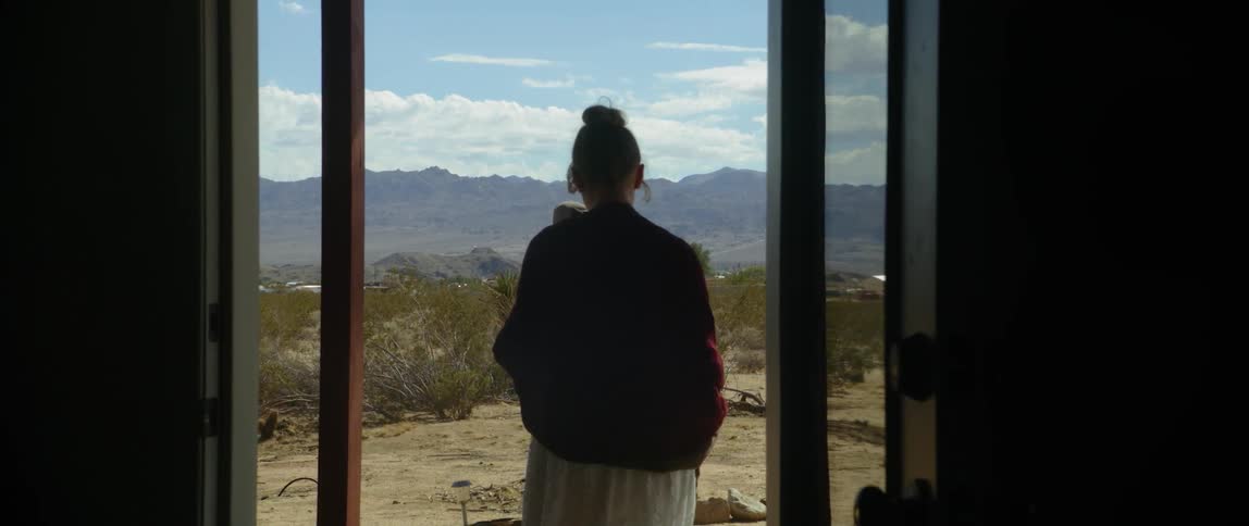 Woman walks past camera and outdoors through a door