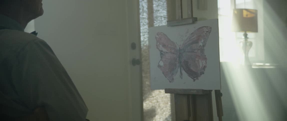 A male artist painting a butterfly on a canvas