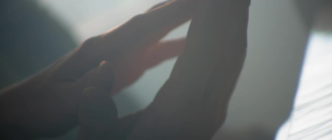 A man and woman's hands clasping in the bedroom