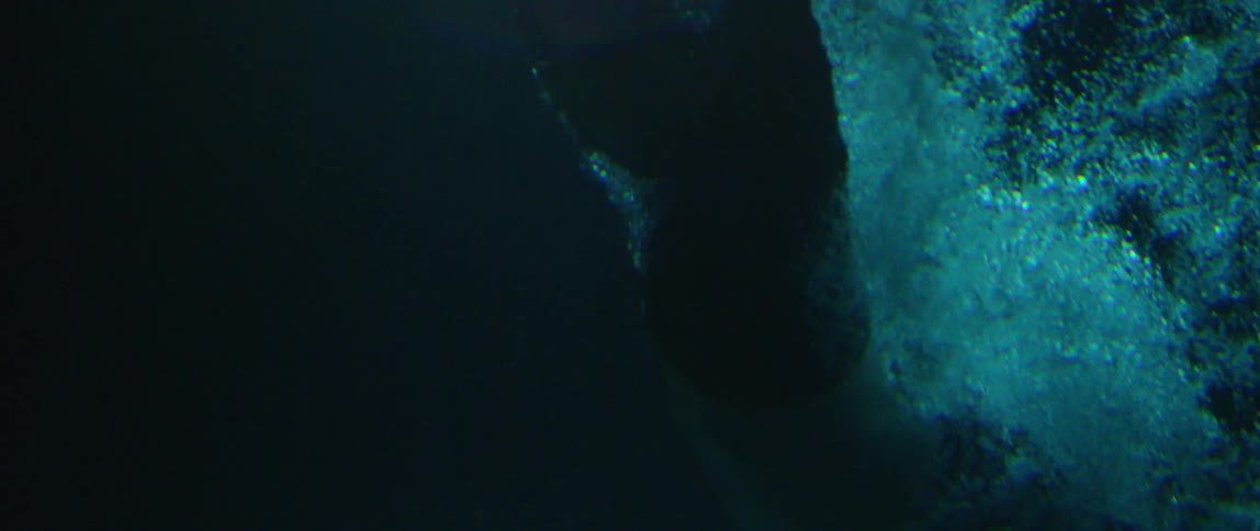 A shadowy human figure sinking into deep water
