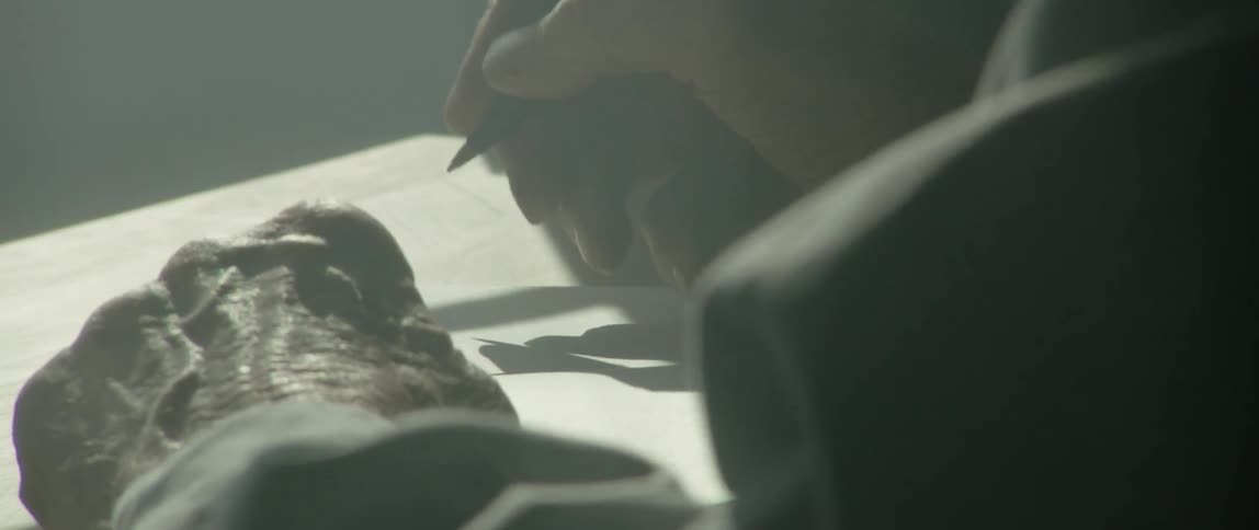 Old man writes on paper in dim light