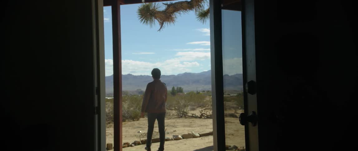 A person walking away from a house into the desert