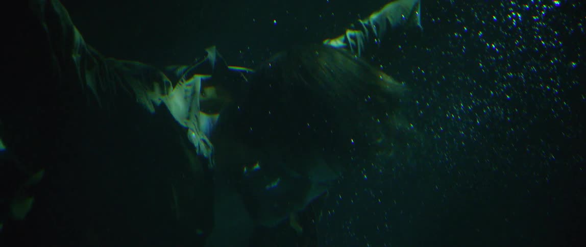 A clothed man sinks and swims underwater