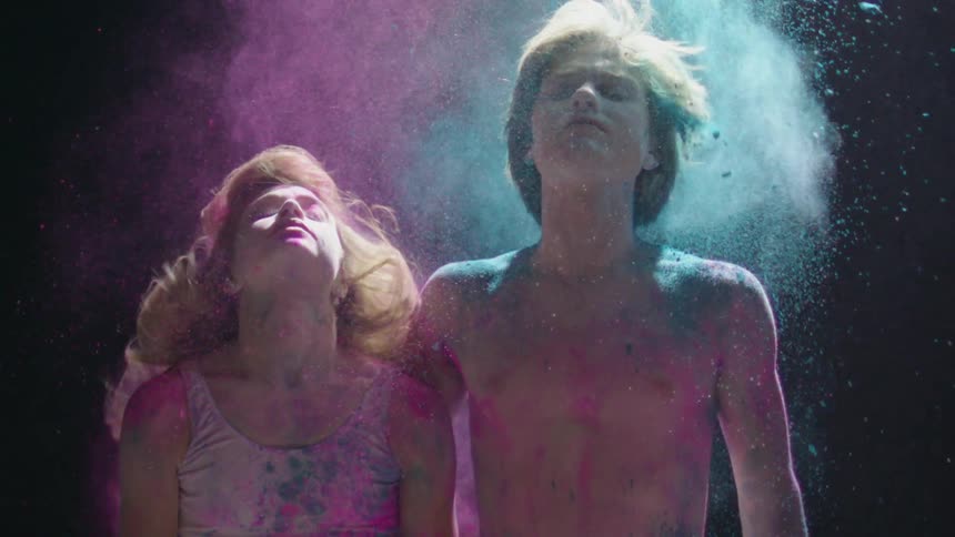 Man and woman dancing in a cloud of colored particles