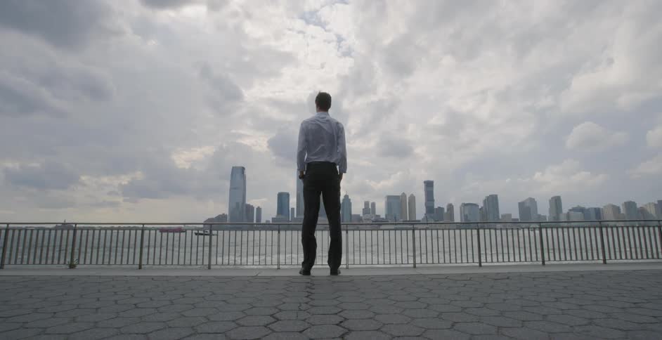 A man stands and looks at city skyscrapers in the distance