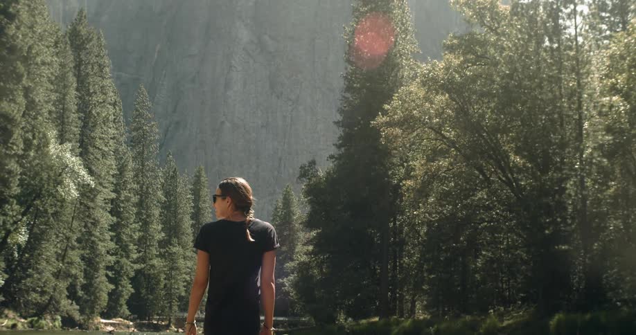 A woman is standing in the water near a mountain