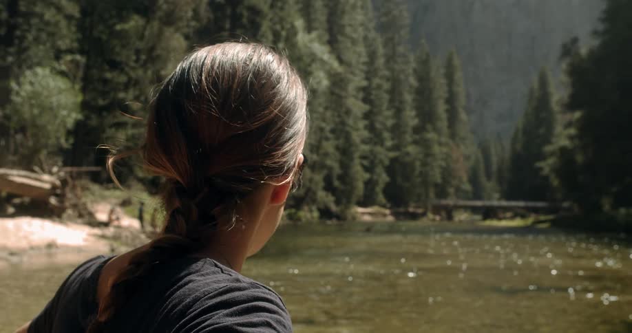 A woman standing next to a stream and staring