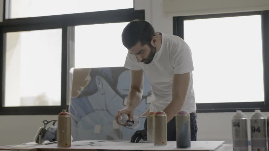 A man is spray painting in the studio