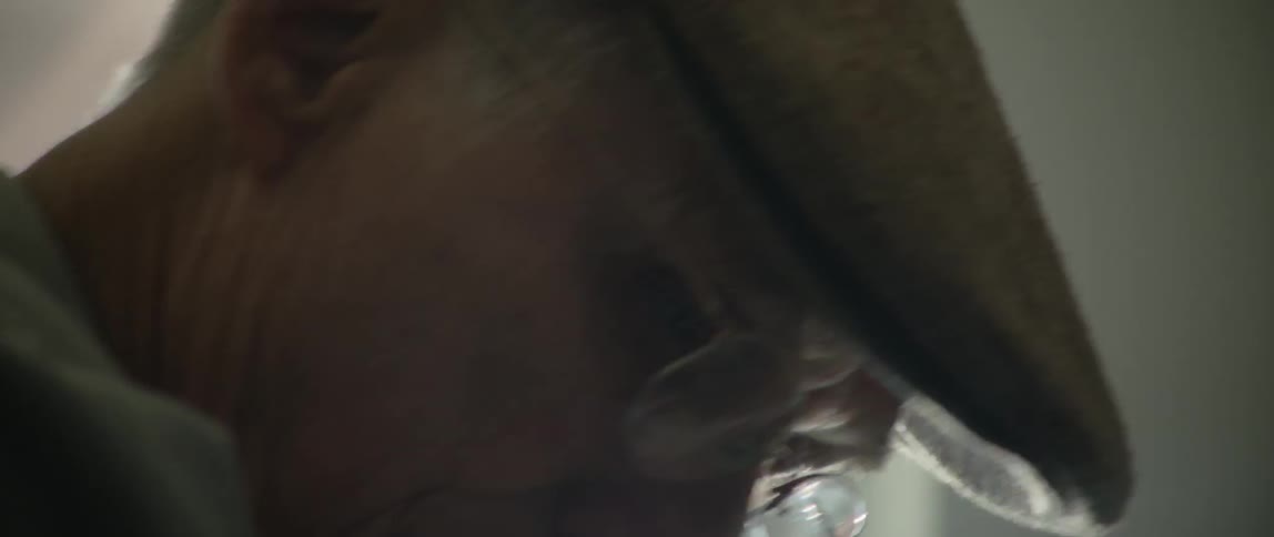 A man wearing glasses and a cap looks down and to the side then straight ahead