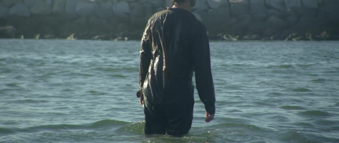Fully clothed person stands in ocean up to their knees