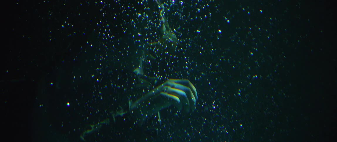 The person is floating under the dark water