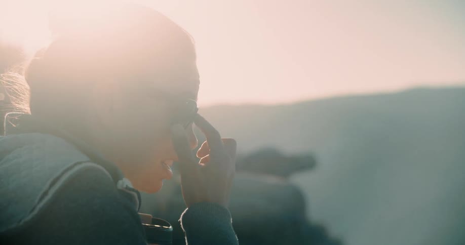 A woman adjusts her sunglasses outside on a sunny day