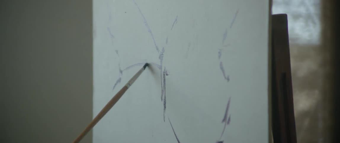 Artist painting a rough butterfly onto a canvas
