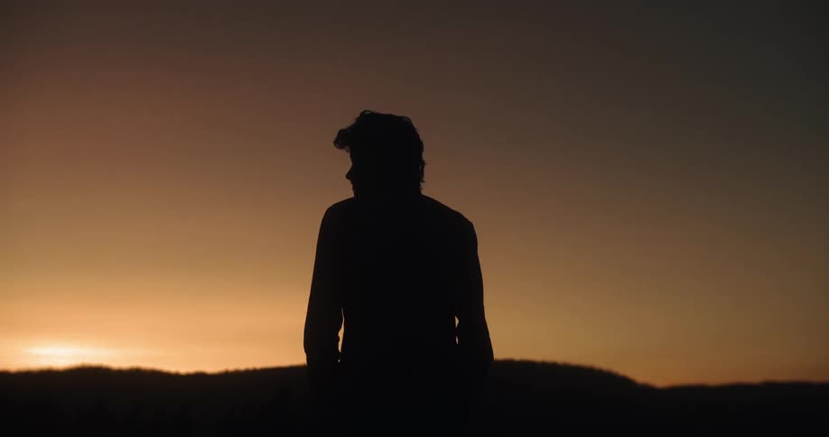 Man turns his head to the left at sunset