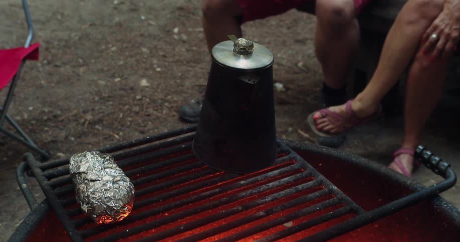 People cook and sit by the grill outside