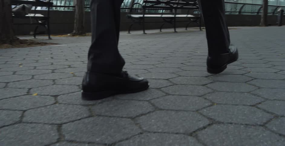 Person walks along paved walkway next to railing among others