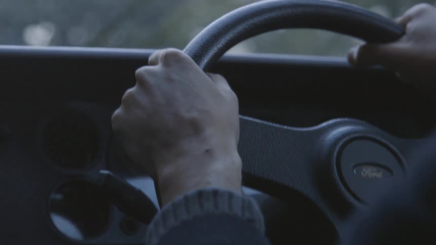 Person holds onto a steering wheel while driving