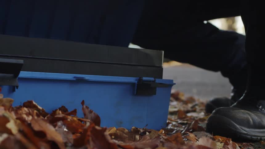 Man puts a tool box on the ground then opens it