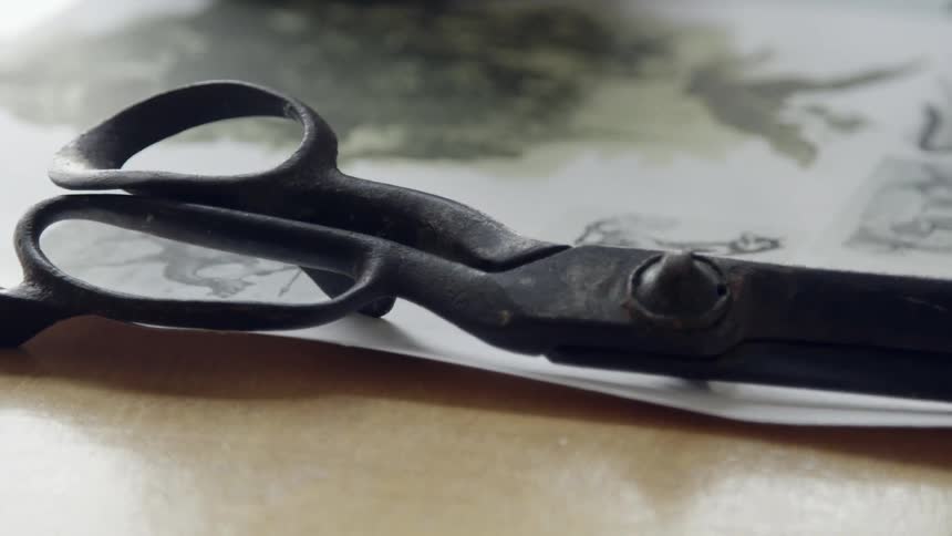 A pair of old scissors on a sketch pad on a desk