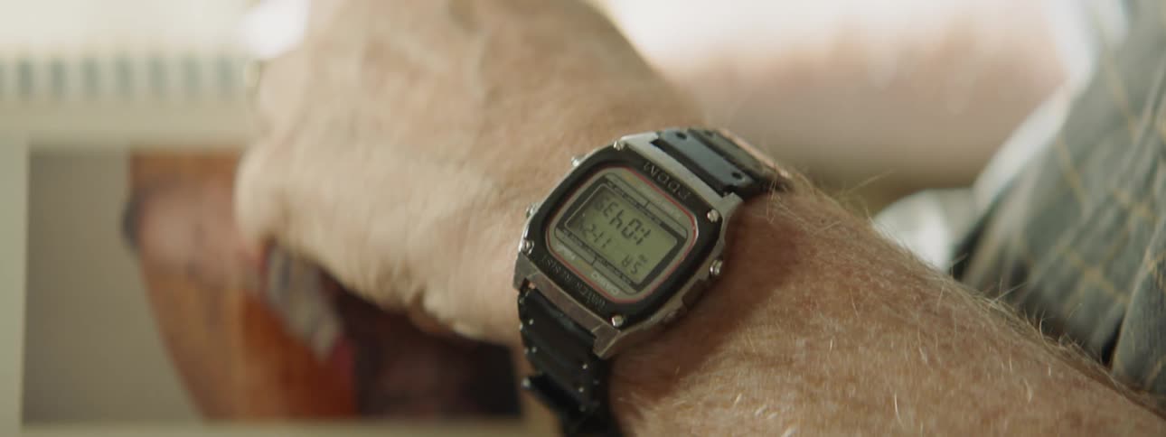 An old man wearing a wristwatch leafs through a photo album