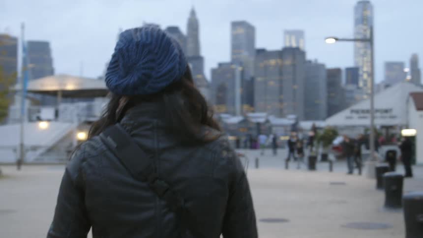 Woman walks towards a crowd and a busy city