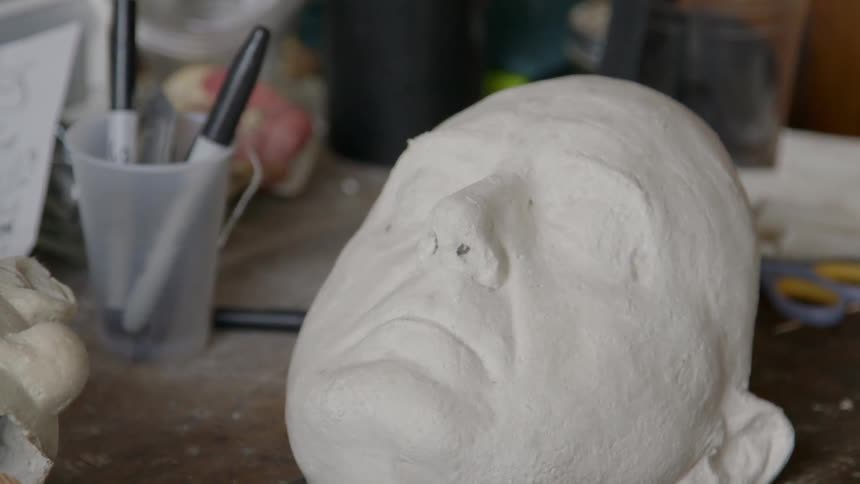 An unfinished mask laying on a work table
