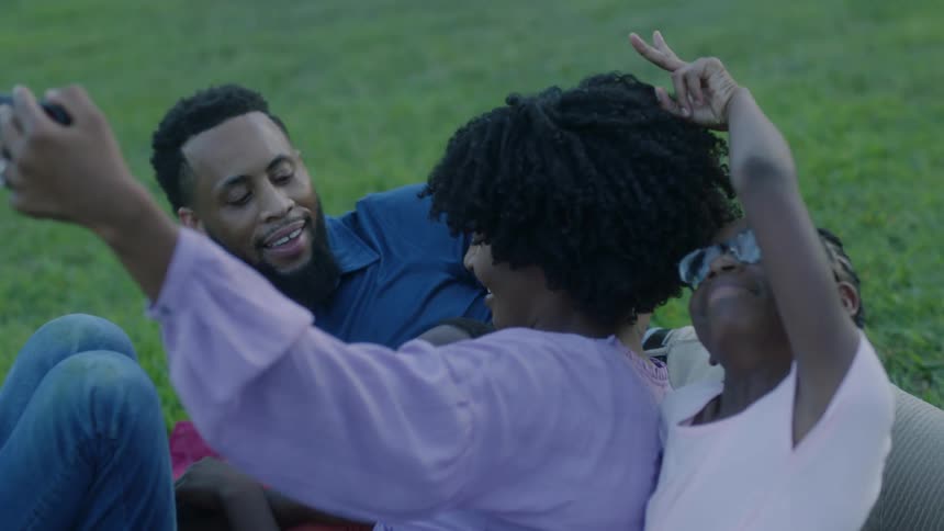 A young family pose together for a picture on the grass