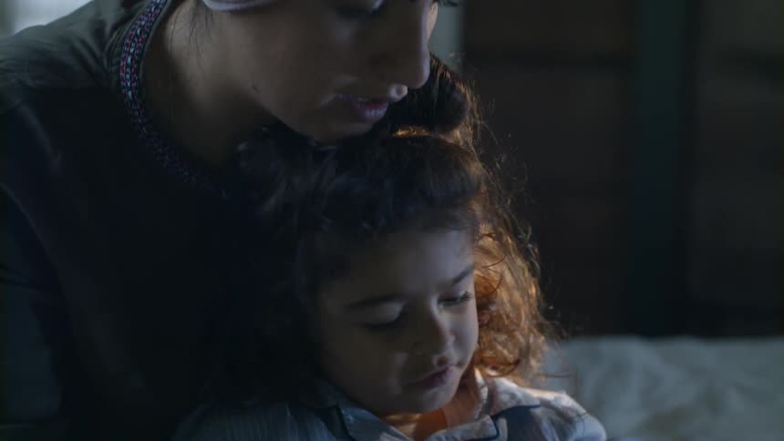 Woman holding a child while they discuss something off camera