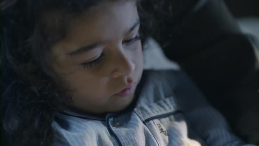 A child talks as she reads in bed
